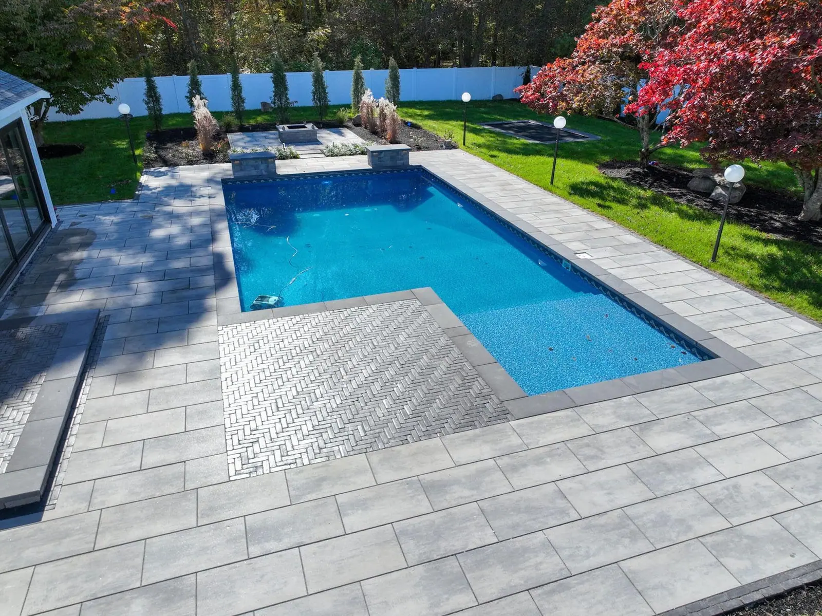 Beautiful backyard pool installation with stone paver patio in Kingston, MA