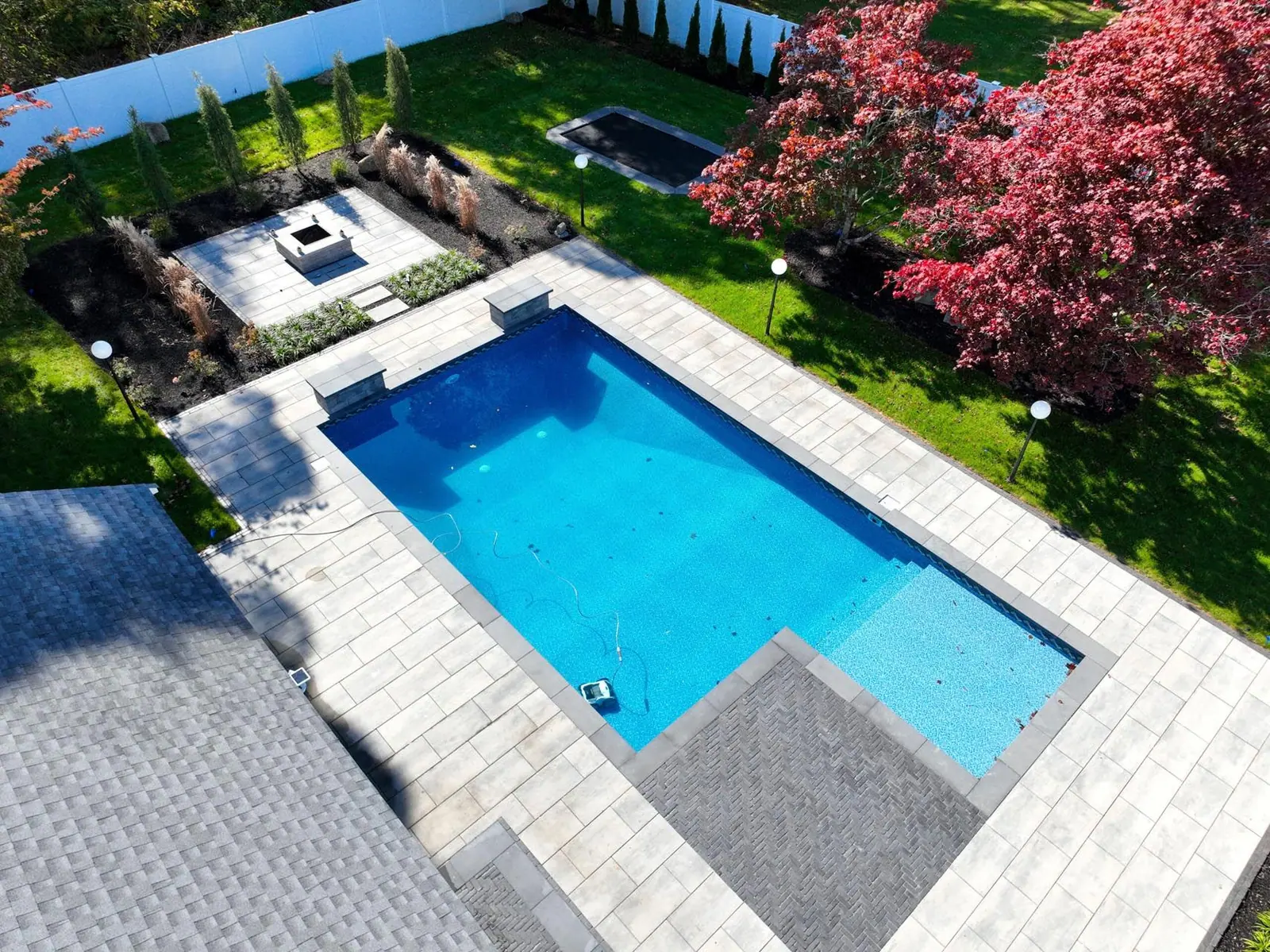 Completed residential swimming pool with custom paver patio surround in Duxbury, MA